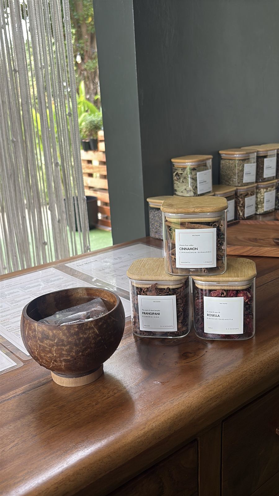 Labeled jars of dried Balinese herbs at the herb bar